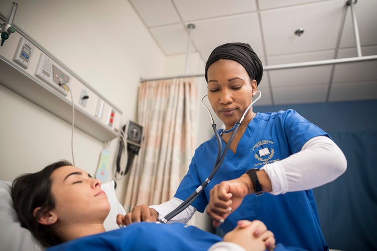 Student nurse with stethoscope taking vitals on female