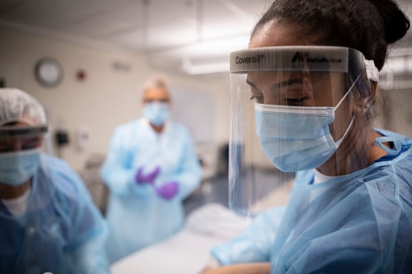 Student in face shield in SIM lab with instructor in background