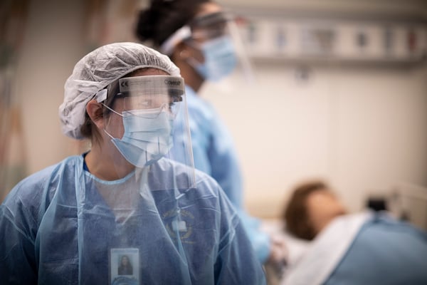 Nursing students wearing mask, gown and face shield in simulation lab 