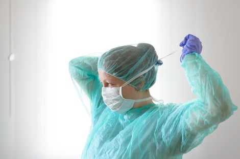 Female Nurse getting putting on mask and hair covering