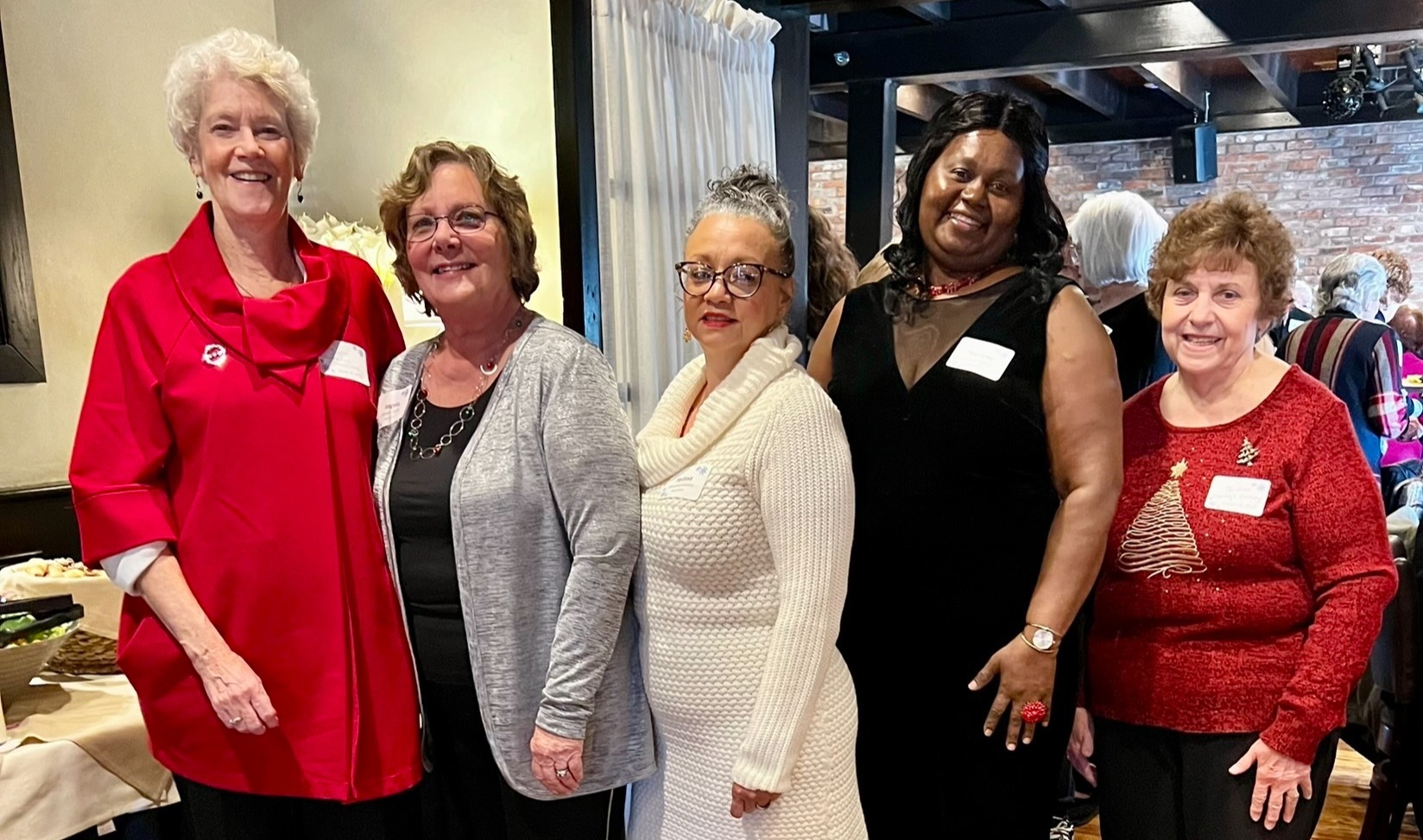 5 women in holiday garb standing at a buffet line